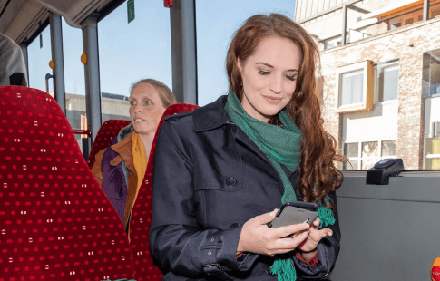Vrouwelijke reiziger in de bus op haar telefoon