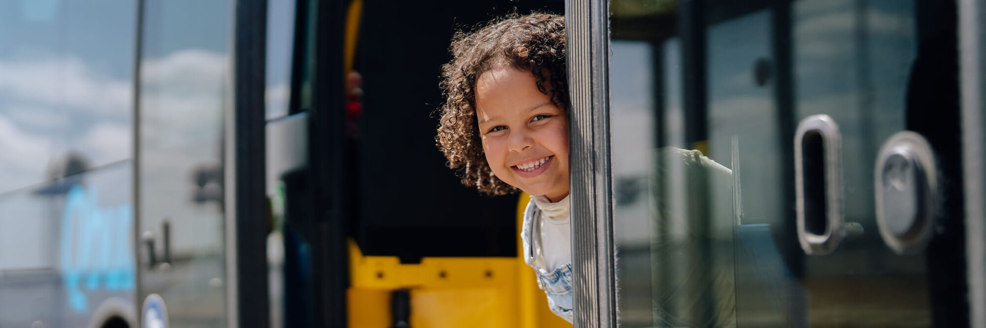 Klein kind kijkt glimlachend bij de deuropening naar buiten